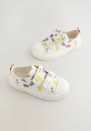 Witte canvas sneakers met een rubberen zool, voorzien van multikleuren geometrische patronen, twee klittenbandsluitingen en een klein bruin hieltabblad.