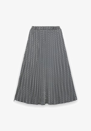 Gonna a pieghe bianca e nera con motivo a zigzag e vita elastica, lunghezza media, distesa su uno sfondo bianco.