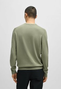 Olivgrüner Strickpullover mit langen Ärmeln, gerippten Bündchen und Saum. Glatte Textur, Rundhalsausschnitt-Design und minimale Nähdetails.