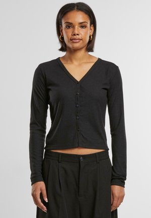 Top noir à manches longues en V avec fermeture à bouton, en tissu côtelé, présentant un design cropped et une silhouette ajustée.