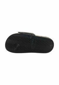 Suola di scarpa in gomma nera con un motivo a zigzag testurizzato. Presenta un logo circolare e una chiusura in Velcro per una vestibilità regolabile.