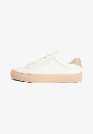 Zapatilla blanca de corte bajo con suela y talón beige, logotipo en el lateral y cordones blancos.