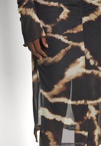 Robes à manches longues avec un motif tie-dye noir et marron, en tissu transparent, fentes sur les côtés et détails froncés aux épaules et à la taille.