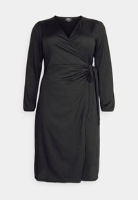 Vestido negro envolvente con mangas largas, escote en forma de V, detalle fruncido en el costado y cierre con lazo en la cintura. Tejido suave con una textura sutil.