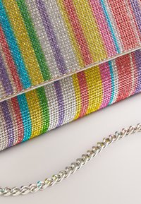 Clutch purse with colorful vertical stripes of rhinestones and a silver chain strap on a neutral background.