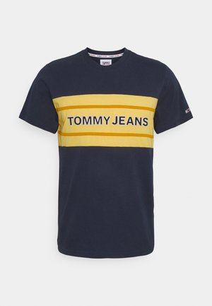 Camiseta de manga corta azul marino con rayas horizontales amarillas y el logo "TOMMY JEANS" centrado en el pecho.