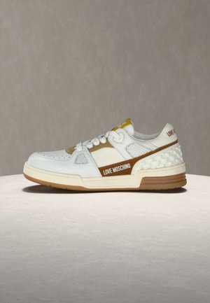 White and beige Love Moschino sneaker with heart-patterned heel, lace-up design, and branded side stripe on gray background.