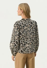 Bluse im Leopardenmuster aus strukturiertem Stoff, mit gerafften Schultern und Ballonärmeln. Verfügt über einen Rundhalsausschnitt und eine lockere Passform.