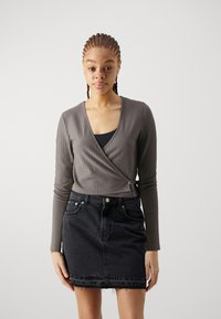 Gray ribbed wrap top with long sleeves, paired with a black denim skirt featuring a frayed hem and front pockets.