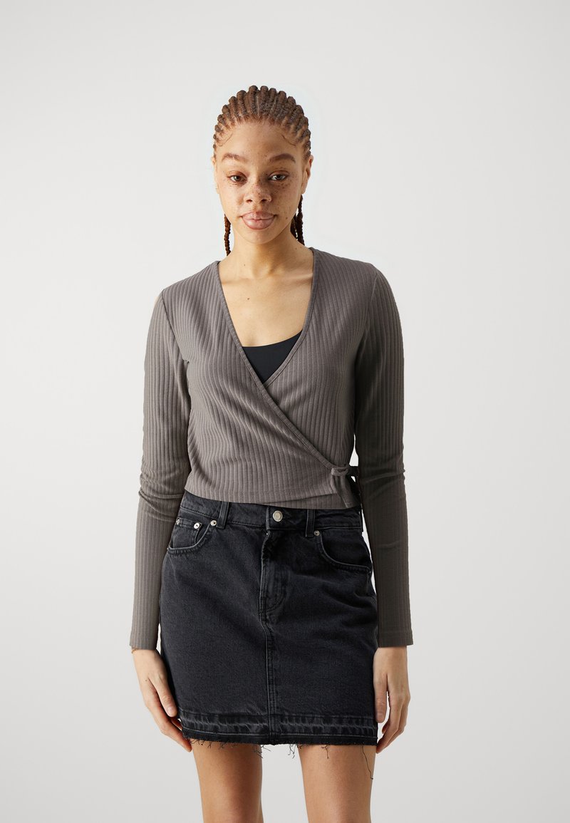Gray ribbed wrap top with long sleeves, paired with a black denim skirt featuring a frayed hem and front pockets.