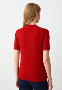 Rode gebreide short-sleeve top met een ronde halslijn, ribbelboorden en zoom. Zachte textuur en aansluitende pasvorm. Minimalistisch ontwerp, geen zichtbare patronen.