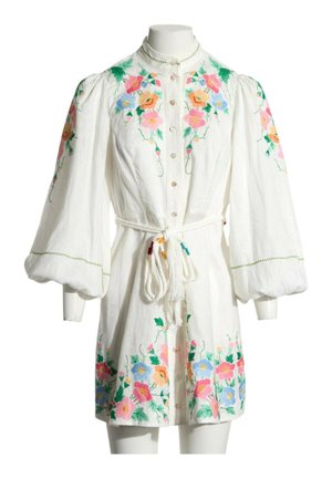 Robe blanche à manches longues avec broderie florale colorée, patte boutonnée devant, manches bouffantes et ceinture en corde nouée à la taille.