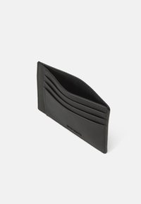 Portofel de carduri din piele neagră, cu mai multe sloturi pentru carduri, textură netedă, linii clare și un design minimalist. Fără branding vizibil pe față.