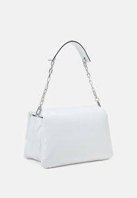 Borsa bianca in similpelle con una forma morbida, fondo piatto e tracolla in catena argentata, dotata di un manico superiore in similpelle bianca.