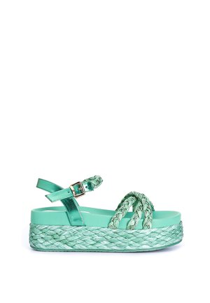 Sandalia de plataforma verde menta con tiras trenzadas, hebilla ajustable en el tobillo y suela tejida con textura.
