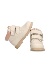 Botines beige de cuero con tiras de velcro, suelas de goma y un acento de fieltro rosa en el talón, con un detalle de estrella.