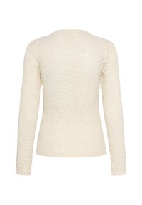 Top din dantelă crem cu mâneci lungi, având un model floral texturat și un guler rotund, care prezintă o siluetă ajustată.