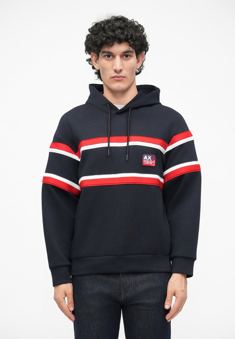 Sudadera azul marino con capucha, con rayas horizontales rojas y blancas, parche de logo en el pecho y puños y dobladillo acanalados.