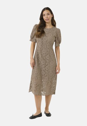 Lace midi dress in light brown with puff sleeves, floral pattern, round neckline, and side slits. Paired with black ballet flats.