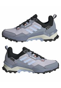 Hellgraue Wanderschuhe, die für den Außenbereich konzipiert sind, mit einem atmungsaktiven Obermaterial, schwarzen Akzenten, einer robusten Sohle und einer verstärkten Ferse.