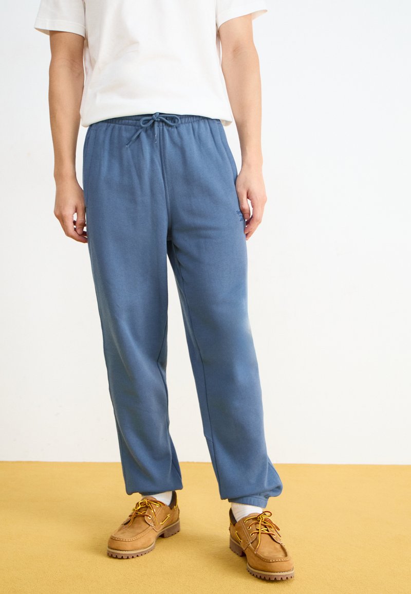 Pantalons de survêtement bleu avec une taille élastique et un cordon de serrage. Fabriqués en tissu doux avec une coupe décontractée. Détails avec des poches latérales.