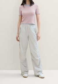 Top de punto acanalado a rayas en rosa y azul, combinado con pantalones cargo ligeros en gris claro, que cuentan con bolsillos laterales y una cintura elástica.