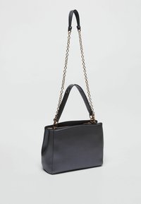 Sac fourre-tout en cuir noir avec une texture lisse, doté d'une chaîne et d'une sangle en cuir. Forme structurée et fermeture zippée sur le dessus.