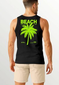 Schwarzes Tanktop mit einem großen neongrünen Palmenmotiv und dem Text "BEACH Social Club 1976" auf der Rückseite, mit zusätzlichen Details darunter.