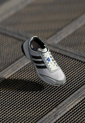 Lightweight running shoe featuring a white mesh upper with three black stripes, gray accents, and a textured sole for grip.