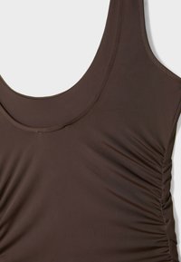 Brown one-piece swimsuit with a scoop neckline and gathered fabric detail on the side. Made of soft, stretchy material.