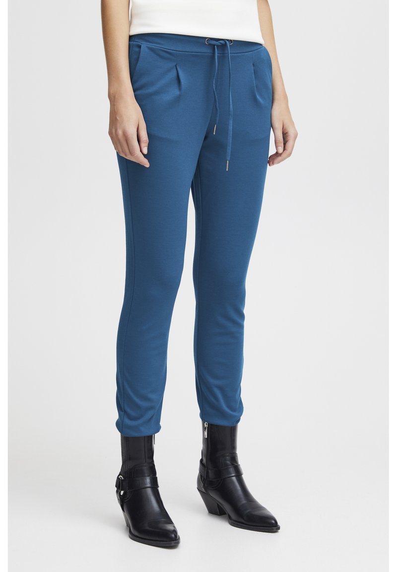 Blå joggerbyxor i mjukt material, med tapered passform, elastisk midja med dragsko och sidofickor. Matchas med svarta ankelstövlar.