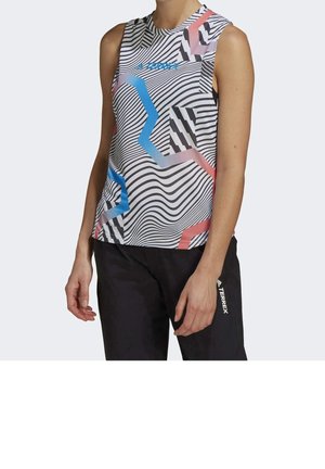 Haut de sport sans manches avec des rayures ondulées noires et blanches et des lignes géométriques bleues et roses, porté avec un pantalon noir.