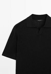 Černé polo tričko s krátkým rukávem, ribovanou strukturou, výstřihem do V a plochým límečkem. Viditelná etiketa s názvem značky "Massimo Dutti."