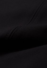 Must mustriga, pehmea tekstuur ja nähtavad õmblusread; omab siledat, veidi venivat välimust, millel on mati viimistlus.