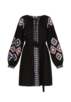 Schwarzes Kleid mit langen Ärmeln, das mit buntem geometrischen Stickerei in Rot, Blau und Weiß verziert ist, sowie einem Bindegürtel in der Taille.