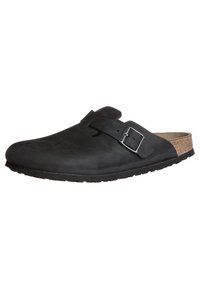 Schwarze Clogs zum Hineinschlüpfen mit einer glatten Lederaußenseite, verstellbarem Metallverschluss und Korkfußbett. Dicke Gummisohle mit strukturiertem Profil.