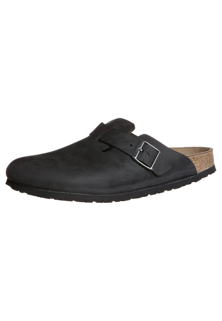 Schwarze Clogs zum Hineinschlüpfen mit einer glatten Lederaußenseite, verstellbarem Metallverschluss und Korkfußbett. Dicke Gummisohle mit strukturiertem Profil.