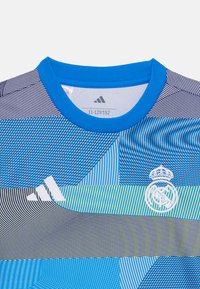 Maglietta a maniche corte a righe blu e grigie con scollatura rotonda, caratterizzata dal logo Adidas e dallo stemma del Real Madrid in bianco.