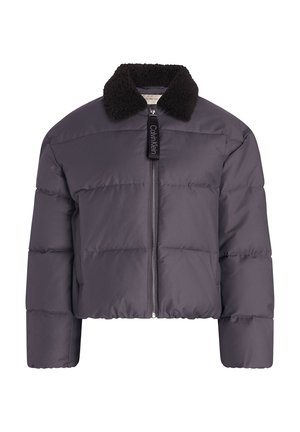 Tamno siva kratka puffer jakna s patentnim zatvaračem, koja ima crni jastučić sa krznom i oznaku Calvin Klein. Mekana, quilted tekstura.
