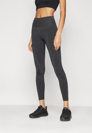 Sorte treningsleggings med en teksturert, glitrende finish, høy midje og dekorative sømmer, kombinert med sorte sneakers.