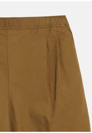Pantalon en tissu avec une ceinture élastique marron, une texture lisse et des coutures visibles près de la ceinture sur un fond clair.