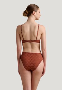 Brun mönstrad bikinitopp med en strukturerad design, justerbara remmar och krokstängning. Högmidjade underdelar kompletterar bh:n.