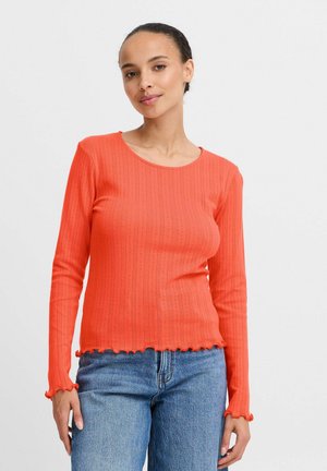 Long-sleeve, ribbed, orange top with a round neckline and scalloped hem. Features textured detailing along the fabric and sleeve edges.