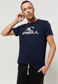 Navyblauwe katoenen t-shirt met een rond logo en "O'NEILL" in witte tekst. Korte mouwen met een relaxte pasvorm. Geselecteerd in combinatie met zwarte joggingbroek.