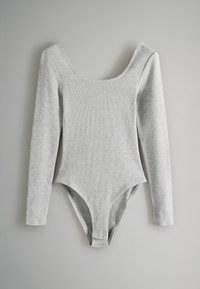 Langærmet grå bodysuit lavet af blødt, ribbet stof. Har en scoop-halsudskæring og trykknaplukning i bunden, med en tætsiddende silhuet.