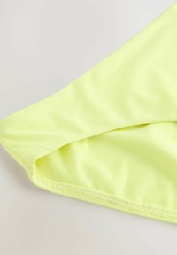 Neon gul tyg med en slät yta, som har en vikt kant och synlig sömnad, vilket visar upp en enkel design.