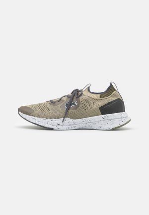 Beige og grå strikket atletiksneaker med spraglet hvid sål, elastisk ankelkrave, snørebånd og logo på siden.
