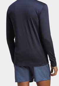 Granatowa koszula z długim rękawem, wykonana z gładkiego, lekkiego materiału, zestawiona z jasnoniebieskimi szortami. Posiada prosty, dopasowany krój oraz okrągły dekolt.