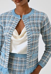Cardigan lavorato a maglia blu chiaro e grigio con motivo a quadretti, dotato di scollatura tonda, apertura frontale e orlo con frange.