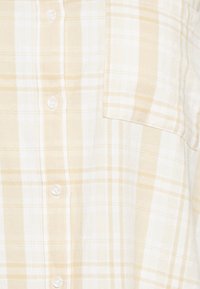 Camisa xadrez em branco e bege claro com fecho de botões, mangas curtas e um bolso no peito. Tecido suave com padrão quadriculado.